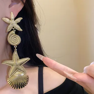 Detailansicht der übergroßen goldenen Seestern- und Muschelohrringe an einem Model getragen