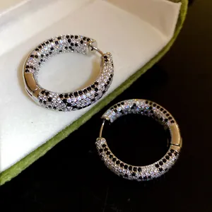 Dettaglio di orecchini a cerchio placcati oro 18K con zirconi bianchi e neri