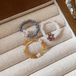 Detailed view of three handmade vintage glass bead flower rings in a jewelry display box