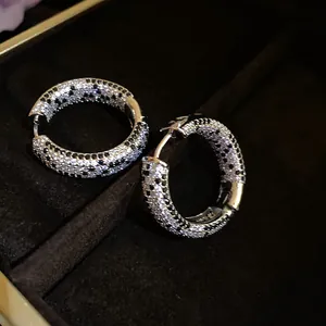 Primo piano degli orecchini a cerchio con pavé di zirconi neri e bianchi di lusso