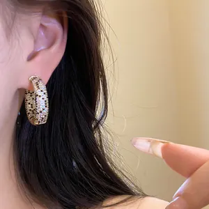 Dettaglio di orecchini a cerchio placcati oro 18K con pietre di zircone bianche e nere