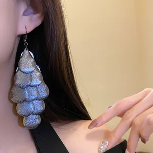 Detailed view of matte metallic teardrop fringe earrings worn by an elegant model