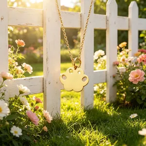 Detailed close-up of a golden stainless steel paw print pendant necklace in a garden.