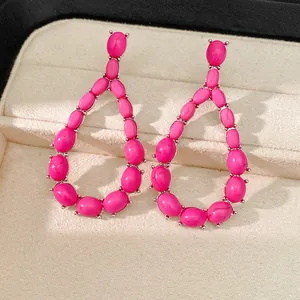 Primo piano di eleganti orecchini a goccia in pietra rosa shocking in un astuccio