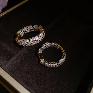 Primo piano di orecchini a cerchio placcati oro 18K con pavé di zirconi bianchi e neri