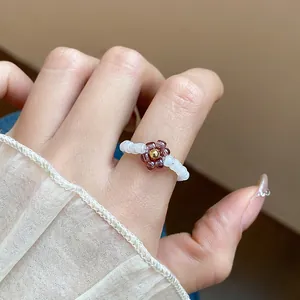 Macro detail of a vintage purple beaded flower elastic ring on a finger.