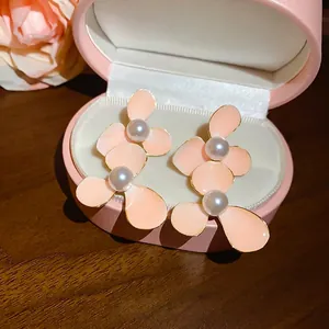 Elegant pink enamel flower stud earrings with white pearl centers in a pink jewelry box
