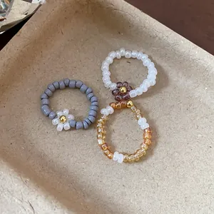 Macro close-up view of retro glass beaded flower elastic rings in diverse earthy tones on a tray