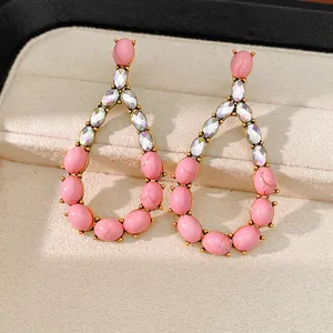 Dettaglio ravvicinato di orecchini a goccia con pietre rosa e strass scintillanti
