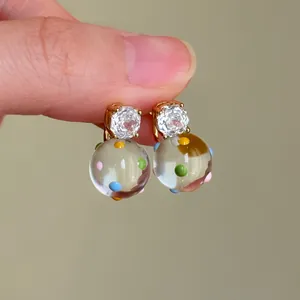 Dettaglio di orecchini a sfera a pois colorati con perni in zircone scintillante oro