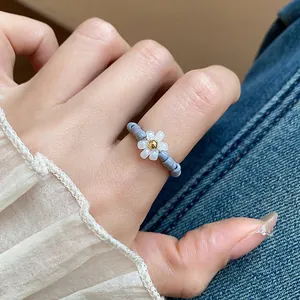 Close-up view of a vintage handmade beaded daisy flower elastic ring worn on a finger