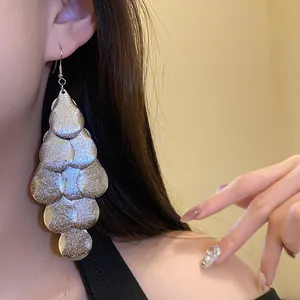 Detail shot of matte silver tiered teardrop earrings worn by model for retro style