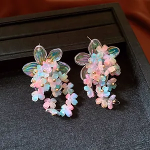 Close-up of colorful acrylic flower cluster earrings with iridescent petals and gold beads