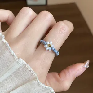 Close-up of a delicate handmade glass beaded flower elastic ring in blue and white