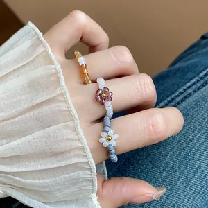 Detailed macro shot of vintage glass beaded flower rings worn on a hand with white sleeve