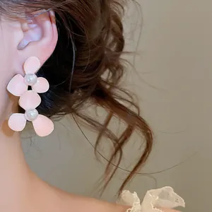 Detailed view of pink drip oil flower earrings with pearls worn on female model's ear.