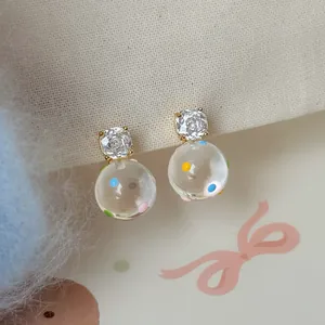 Primo piano di orecchini a pois dolci con perni in zircone scintillante