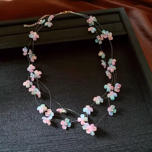 Close-up of a multi-layered necklace featuring delicate pink and blue acrylic flowers