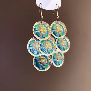 Detailed macro view of gold-tone layered earrings with vibrant floral enamel prints.