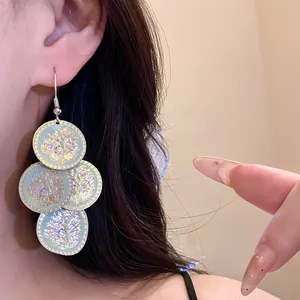 Close-up of bohemian style drop earrings with iridescent floral printed discs.