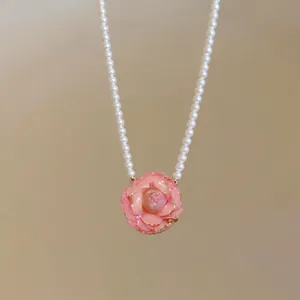Elegant pearl necklace featuring a delicate pink rose pendant in a romantic style.