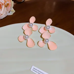 Detailed view of pink flower earrings with pearl centers on a green ceramic plate