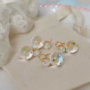 Dettaglio di orecchini a lobo placcati oro 18k con zircone e sfere a pois multicolore