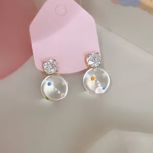 Dettaglio macro di orecchini a pois trasparenti con zirconi brillanti e placcatura oro 18k