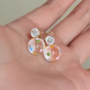 Dettaglio di orecchini placcati oro 18k con zirconi e sfere di vetro a pois colorati