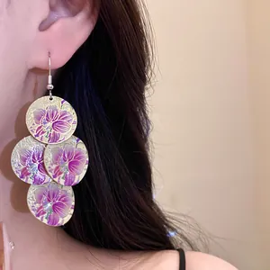 Close-up detail of purple floral oil drip disc drop earrings worn on a model's ear