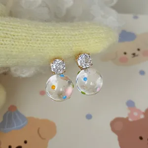 Dettaglio di orecchini placcati oro 18k con zirconi e sfere di vetro a pois colorati