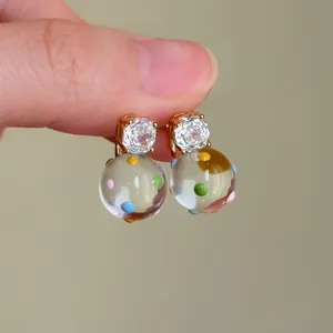Primo piano di orecchini placcati oro 18k con zircone trasparente e perla a pois.