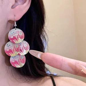 Detail of tulip printed earrings with red oil drip finish and butterfly patterns