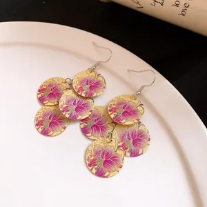 Detail view of statement gold earrings with purple floral print and round charms