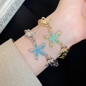Elegant gold and silver starfish and seashell charm chain bracelets worn on a wrist