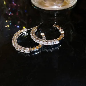 Close-up detail of C-shaped hoop earrings featuring sparkling cubic zirconia stones