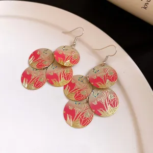 Macro shot of the intricate floral and butterfly design on red enamel tiered earrings.