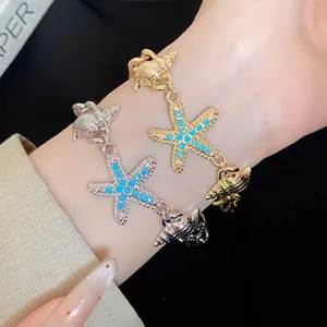 Close-up of conch and starfish charm bracelets with blue inlay on wrist