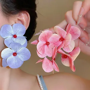 Primer plano de pendientes de flores artificiales grandes con textura realista.