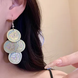 Close-up view of floral print geometric tassel drip oil earrings worn on a model's ear