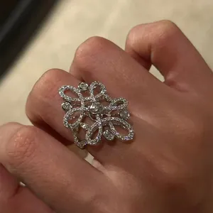 Detailed close-up shot of a vintage style hollow flower ring with zircons on a hand