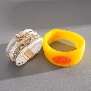 Detailed view of white multi-layer leather heart bracelet and yellow resin bangle