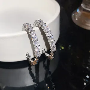 Close-up of elegant silver-colored C-shaped hoop earrings with sparkling cubic zirconia