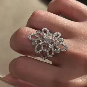 Detailed view of a vintage hollow flower ring with pavé-set cubic zirconia on a finger.