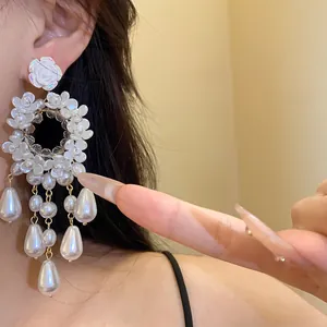 Close-up of vintage resin floral earrings with pearl teardrop charms on model