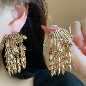 Close-up detail of golden wheat leaf tassel earrings worn on a model's ear for high-end look