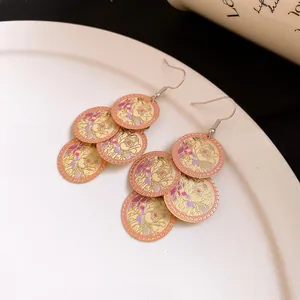 Close-up detail of gold dangle earrings featuring colorful floral drip oil patterns.