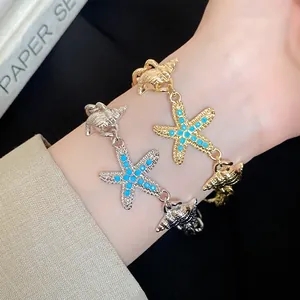 Close-up of gold and silver bracelets featuring turquoise-inlaid starfish and seashell charms