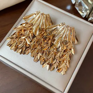 Detail macro shot of elegant golden wheat leaf tassel earrings with high metallic finish
