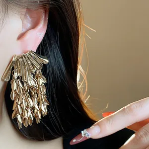 Close-up of gold wheat leaf tassel earrings showing metallic texture and luster.